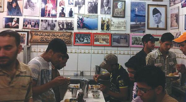 Locals enjoy their kabba surrounded by pictures of famous customers from years gone by. (Asharq Al-Awsat)