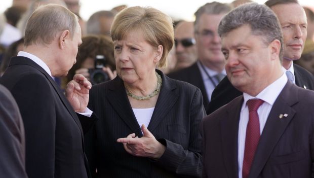 German Chancellor Angela Merkel speaks with Russian President Vladimir Putin (L) as Ukraine's President-elect Petro Poroshenko (R) walks past during the Ouistreham International Ceremony at Sword Beach to commemorate the 70th anniversary of the Allied invasion at Normandy, in Ouistreham, France, June 6, 2014. (AFP PHOTO/SAUL LOEB)