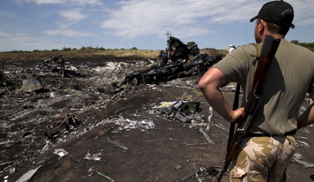 An armed man looks at charred debris at the crash site of Malaysia Airlines Flight 17 near the village of Hrabove in eastern Ukraine, on July 20, 2014.(AP Photo/Vadim Ghirda)