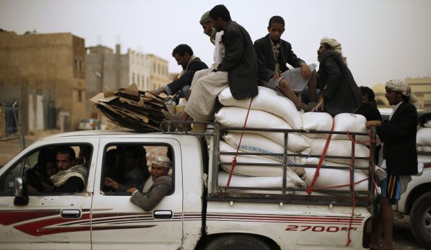 People ride atop a pick-up vehicle after they received foodstuff assistance from a World Food Program distribution center for people displaced by armed conflicts in northern Yemen, in Sana'a on July 21, 2014. (REUTERS/Khaled Abdullah)