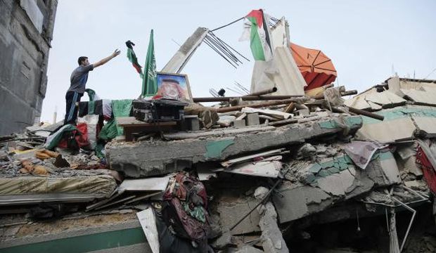 A Palestinian man throws a flag atop the rubble of the home of Hamas Gaza leader Ismail Haniyeh, which Gaza's Interior Ministry said was hit by a missile fired by Israeli aircraft before dawn on Tuesday, causing damage but no casualties, in Gaza City, on July 29, 2014. (Reuters/Finbarr O'Reilly)