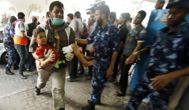 A Palestinian man carries a boy, who medics said was wounded during heavy Israeli shelling at the Shejaia district, at a hospital in Gaza on July 20, 2014. (Reuters/Suhaib Salem)