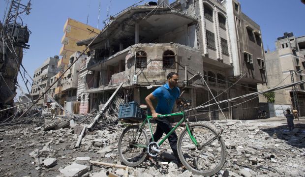 A Palestinian man pushes his bicycle amidst debris following an Israeli military strike in Gaza city, on July 23, 2014. (AFP Photo/Mahmud Hams)