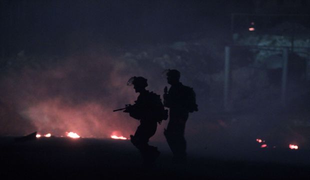 Israeli security officers make their ways past buring tires as at least 10,000 Palestinian protesters marching against Israel's military offensive in the Gaza Strip clash with Israeli soldiers and border police at the Israeli Qalandiya checkpoint, between Jerusalem and Ramallah, on 25 July 2014. (AFP/Abbas Momani)