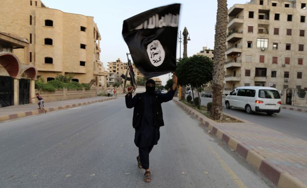 A member loyal to the Islamic State in Iraq and Syria (ISIS) waves an ISIS flag in Raqqa, Syria on June 29, 2014. (Reuters)