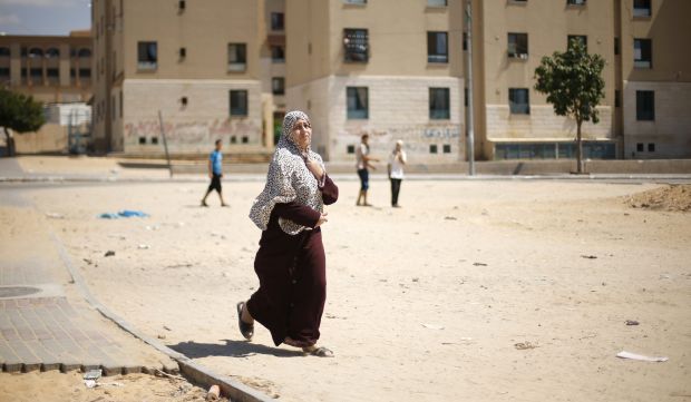 A Palestinian woman flees her house following what witnesses said was a nearby airstrike on an apartment in Beit Lahia in the northern Gaza Strip on August 10, 2014. (Reuters/Mohammed Salem)