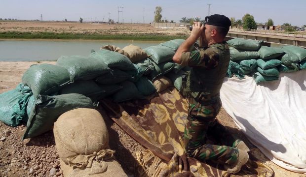 A Peshmerga soldier looks through binoculars from a position as he looks across a canal toward Islamist Jihadist positions south of the oil hub city of Kirkuk, Iraq, on August 17, 2014. (AFP Photo/Marwan Ibrahim)