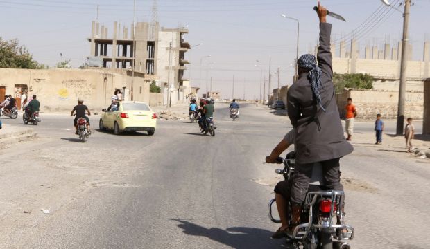 A man holds up a knife as he rides on the back of a motorcycle touring the streets of Tabqa city with others in celebration after ISIS militants took over Tabqa air base, in nearby Raqqa city, Syria, on August 24, 2014. (Reuters/Stringer)