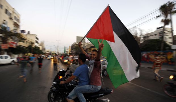 Palestinians wave the national flag as they gather on the streets of Gaza City on August 26, 2014, to celebrate the long-term truce agreed between Israel and the Palestinians. (AFP Photo/Mohammed Abed)