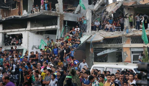 A crowd of Palestinians stand in the rubble of a building that was destroyed during fighting between Hamas militants and Israel as they watch a Hamas parade in the Shejaia district of the Gaza Strip, on August 27, 2014. (AFP Photo/Roberto Schmidt)