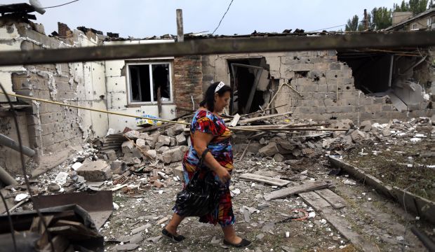 A woman walks past a damaged house in Donetsk on August 11, 2014. Ukrainian troops have been shelling neighborhoods in the city in an attempt to drive out pro-Russian separatists. (AFP Photo/ Max Vetrov)