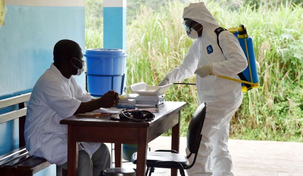 A man wearing a protective suit washes a health center's hallways in Kandopleu village, near Biankouma, Ivory Coast, on August 14, 2014. (AFP Photo/Issouf Sanogo)