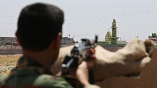 A Kurdish Peshmerga fighter takes his position behind a wall on the front line with militants from the Islamic State of Iraq and Syria, in Tuz Khurmato, Iraq, on Wednesday, June 25, 2014. (AP Photo/Hussein Malla)