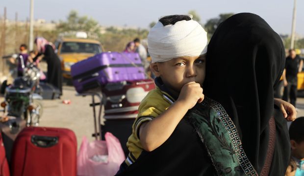 A wounded Palestinian boy, hoping to cross into Egypt with his family, is held by his mother as they wait at the Rafah crossing between Egypt and the southern Gaza Strip August 12, 2014. (Reuters/Ibraheem Abu Mustafa)