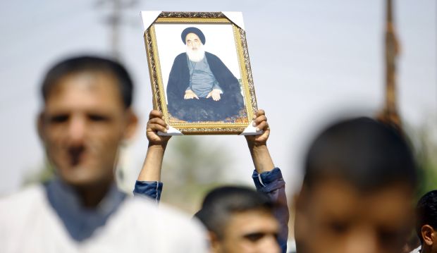An Iraqi man holds up a portrait of Shiite cleric Grand Ayatollah Ali al-Sistani during a demonstration in the central Shiite Muslim shrine city of Najaf on June 14, 2014. (AFP/Haider Hamdani)