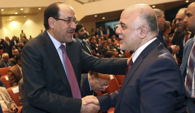 Former Iraqi prime minister Nuri Al-Maliki (L) and the country's new Prime Minister Haider Al-Abadi (R) shake hands during the session to approve the new government in Baghdad, Iraq, on Monday, September 8, 2014. (AP Photo/Hadi Mizban, Pool)