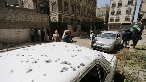 People gather near a car damaged by a mortar shell during fighting between Houthi militants and government forces in Sana'a. (Reuters Photos)