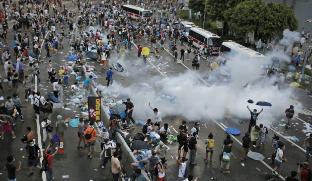 Riot police use tear gas against protesters after thousands of people blocked a main road at the financial central district in Hong Kong, Sunday, Sept. 28, 2014. (AP Photo/Vincent Yu)