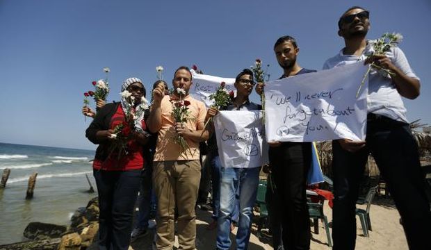 A group of Palestinians prepare to throw roses in the Mediterranean Sea off the coast of Gaza City on September 18, 2014 in mourning over the loss of fellow Palestinians who had boarded a boat to Europe that sank off Malta last week. (AFP Photo/Mohammed Abed)