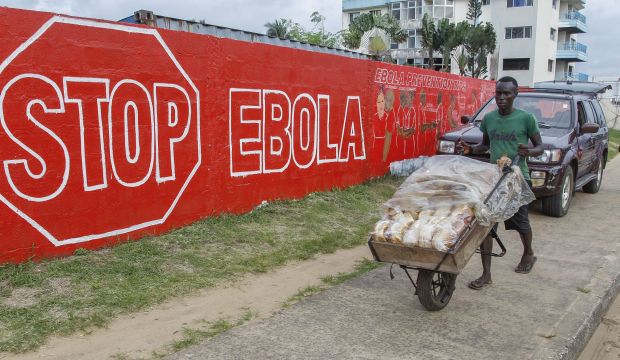 A Liberian man pushes bread past a wall mural, part of a sensitization program about the deadly Ebola virus in Monrovia, Liberia, on 15 September, 2014. (EPA/Ahmed Jallanzo)