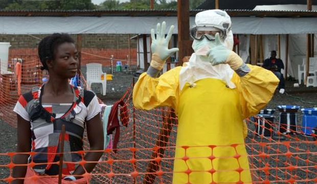 A medical worker wearing Personal Protective Equipment (PPE) gestures beside a woman inside the high-risk area of the Elwa hospital runned by Medecins Sans Frontieres (Doctors without Borders), where are being treated Ebola patients, on September 7, 2014 in Monrovia. (AFP PHOTO / DOMINIQUE FAGET)