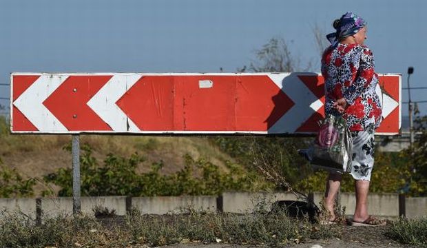 A woman stands next to a road sign on September 7, 2014 after an overnight bombing attack, at an Ukrainian army checkpoint in the outskirts of the key southeastern port city of Mariupol. (AFP Photos)