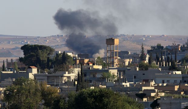 Smokes rise after a mortar shell landed in the south of the city center of Syrian Kurdish town of Kobani, seen from the Turkish side of border as thousands of new Syrian refugees from Kobani arrive in Suruc, Turkey, Wednesday, October 1, 2014.  (AP Photo/Burhan Ozbilici)