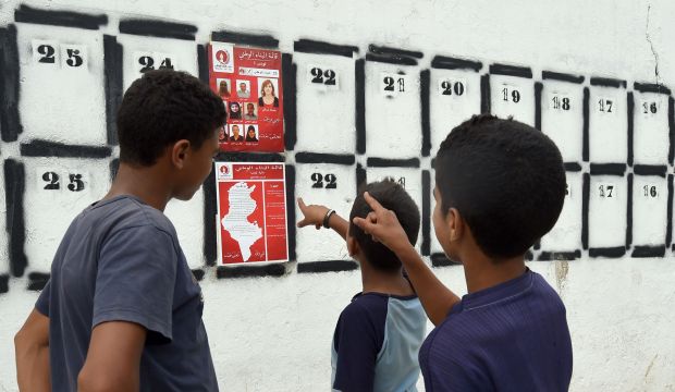 Tunisian youth look at election posters put up on a street in Tunis on October 4, 2014. (AFP Photo/Fethi Belaid)