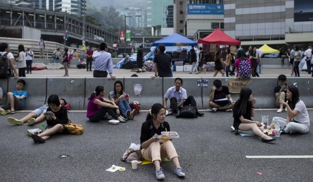 A woman takes her lunch while sitting on a highway, part of an area blocked off by protesters of the Occupy Central movement, in Hong Kong, on October 7, 2014. (Reuters/Tyrone Siu)