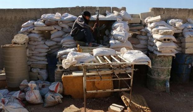 A rebel fighter from the Free Syrian Army (FSA) sits on a barricade as he holds a position on a front line in the northern city of Aleppo on October 1, 2014. (AFP)