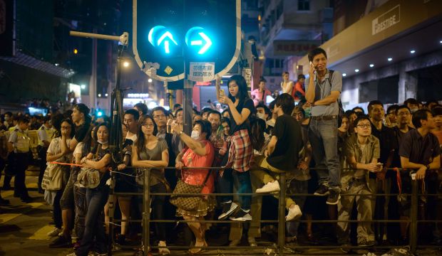 Pro-democracy protesters and bystanders watch the police from behind a cordon in the Mong Kok district of Hong Kong early on October 18, 2014. (AFP Photo/Ed Jones)