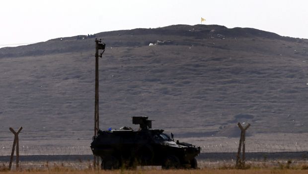 A lone Kurdish flag flutters in the wind next to YPG Kurdish fighters standing on the hill after they took over from ISIS militants near Kobani, Syria. (EPA/Sedat Suna)