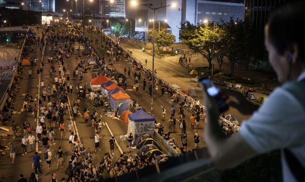 A man takes photos from a footbridge above a barricaded flyover occupied by pro-democracy protestors in the Admiralty district of Hong Kong on October 11, 2014. (AFP Photo/Ahthony Wallace)