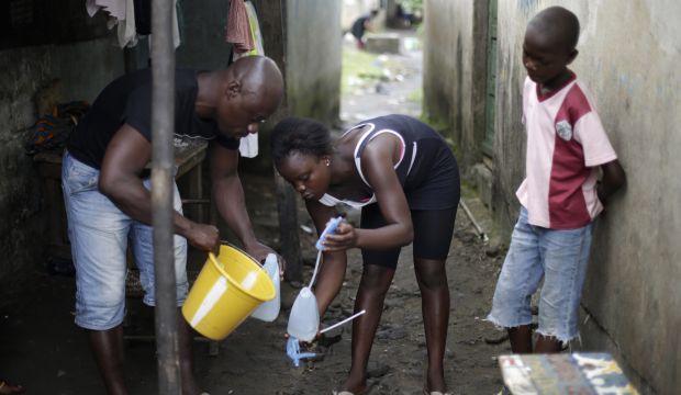 A community activist (L) helps Promise Cooper, 16, and her brother Emmanuel Junior, 11, make a disinfectant solution. The siblings were orphaned after their parents died of the Ebola virus. (AP Photo/Jerome Delay, File)