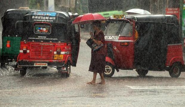 A Sri Lankan resident shelters under an umbrella as she walks through a heavy downpour in Colombo on October 7, 2014. Most of Sri Lanka has seen heavy monsoon rains over the past few weeks. (AFP Photo/Ishara S. Kodikara)
