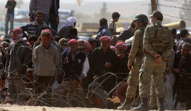 Turkish soldiers guard the Turkey-Syria border as Syrians from Kobani wait behind barbed wire to enter Turkey at the Yumurtalık crossing on October 2, 2014. (AP Photo/Burhan Ozbilici)
