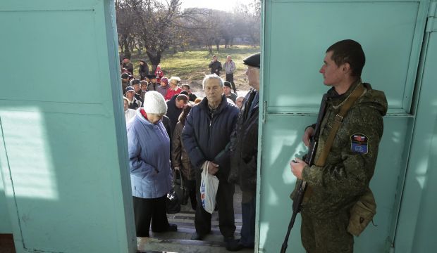 An armed man guards the entrance as local people stand in line outside a polling station during elections in the self-proclaimed Donetsk People's Republic (DNR), in Donetsk, Ukraine, on November 2, 2014. (EPA/ANASTASIA VLASOVA)