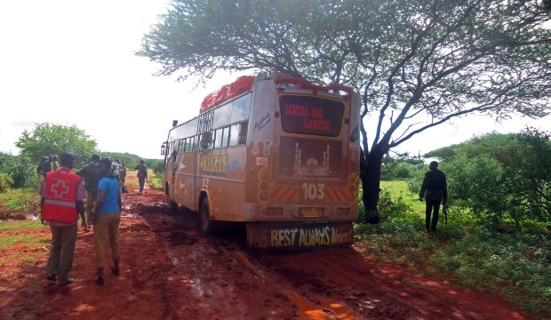 A picture taken on November 22, 2014 shows a medical worker and security forces walking near a bus attacked by militants near the Kenyan-Somalian border. (AFP PHOTO/ STRINGER)