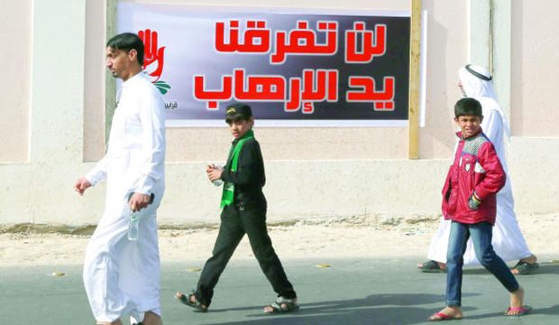 Saudi citizens walk by a sign saying, “Terrorism will not divide us.” (Asharq Al-Awsat/Issa Al-Dossaini) 