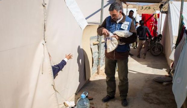 A volunteer from a Lebanese NGO distributes bread to Syrian refugees at the Al-Amaan camp in Arsal, Lebanon, on October 26, 2014. (AFP Photo/Maya Hautefueille)