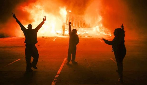 Protestors parade in the parking lot of a burning auto parts store in Ferguson, Missouri, USA, on 24 November 2014. (EPA/Tannen Maury)