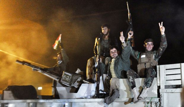 Kurdish Peshmerga fighters  gesture atop a military vehicle armed with a heavy infantry weapon as they ride towards the Syrian town of Kobani from the border town of Suruc, in the Turkish southeastern Sanliurfa province, on October 31, 2014. (AFP) 