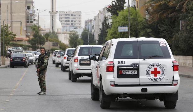A convoy carrying Peter Maurer, president of the ICRC, drives past a member of forces loyal to Syria's President Bashar Al-Assad securing the road in the Damascus suburb of Barzeh on November 14, 2014. (Reuters/Omar Sanadiki)