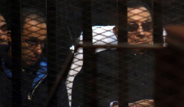 Egypt's former president Hosni Mubarak (R) and his son Gamal sit behind bars during a court hearing on November 29, 2014 in the Egyptian capital Cairo. (AFP Photo)