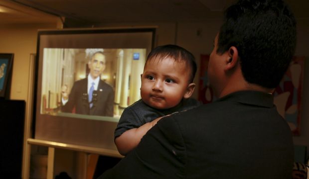 Christian Ramirez holds his nine-month old son Diego while watching President Barack Obama's White House speech on immigration at a viewing party at Alliance San Diego in San Diego, California, on November 20, 2014. (Reuters/Sandy Huffaker)
