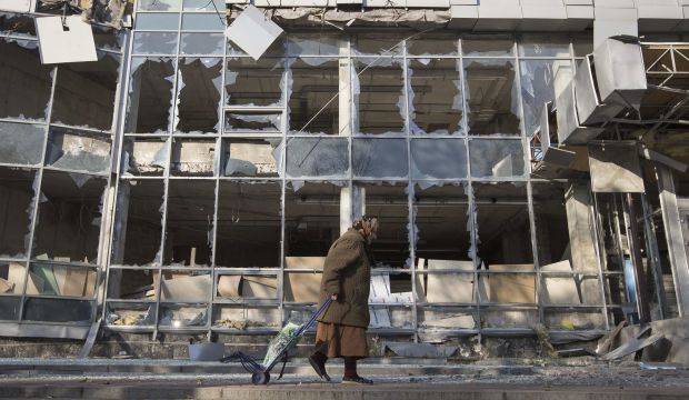 A woman pulls her shopping trolley as she walks past a building that was damaged by shelling in Donetsk, eastern Ukraine. (Reuters/Shamil Zhumatov/Files)