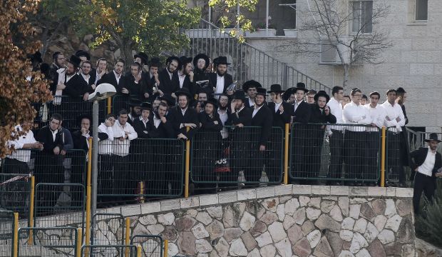 Ultra-orthodox Jews watch emergency personnel clean up and secure the site of the attack on worshipers at a synagogue in Jerusalem on November 18, 2014. (AFP Photo/Ahmad Gharabli)
