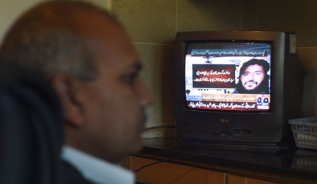 A Pakistani man watches a television broadcasting news of top Al-Qaeda leader Adnan El-Shukrijumah, in Islamabad on December 6, 2014. (AFP PHOTO/Farooq NAEEM)