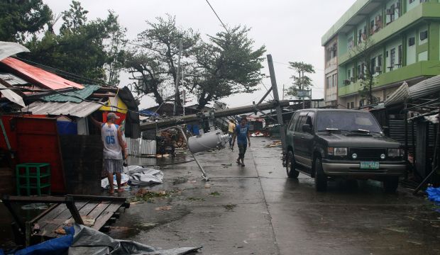 A man walks under a fallen electric post in Tacloban, central Philippines on December 7, 2014. (AFP PHOTO/MARLON TAN)