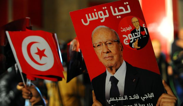 A supporter holds a poster of Tunisian presidential candidate Beji Caid El-Sebsi as he celebrates after the first results following the second round of the country's presidential election, in Tunis, on December 21, 2014. (AP Photos/Hassene Dridi)